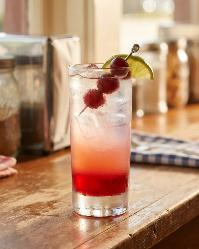 Dirty Shirley i highballglas med cocktailkirsebær og lime