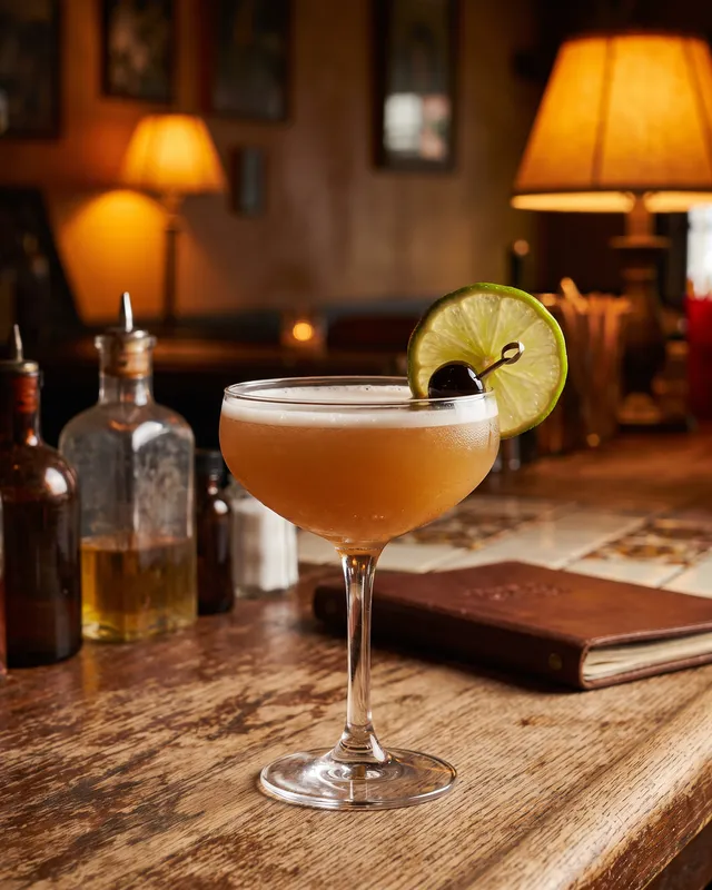 Tequila Sour i coupe med lime og cocktailkirsebær